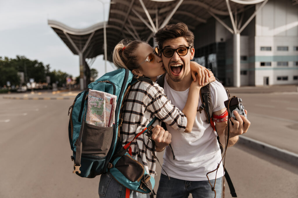 Blonde woman in striped shirt kisses happy emotional man in sunglasses